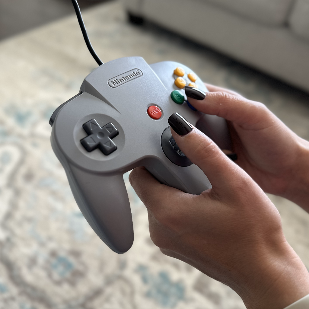 Someone holding a grey nintendo 64 controller